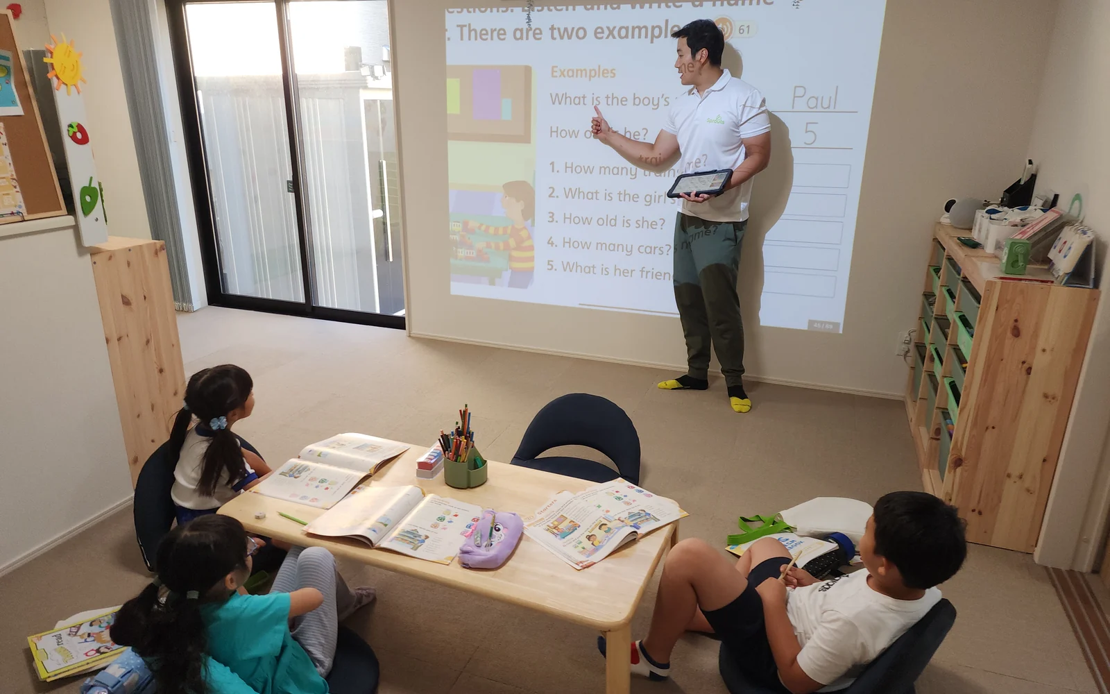 先生がプロジェクターを使って小学生に英語を教えるSproutsのレッスン風景