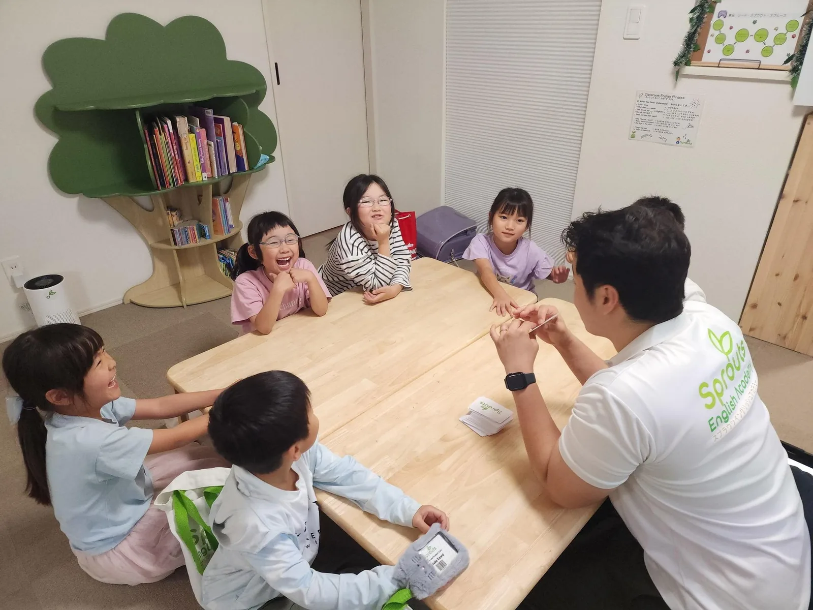 先生と子どもたちがテーブルを囲んで英語でやり取りしている様子